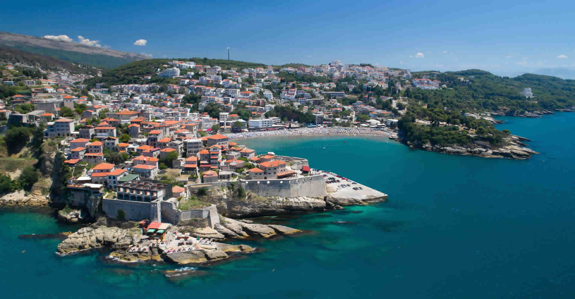 Drone view of Ulcinj Old town and city walls, with beautiful beach next to it.